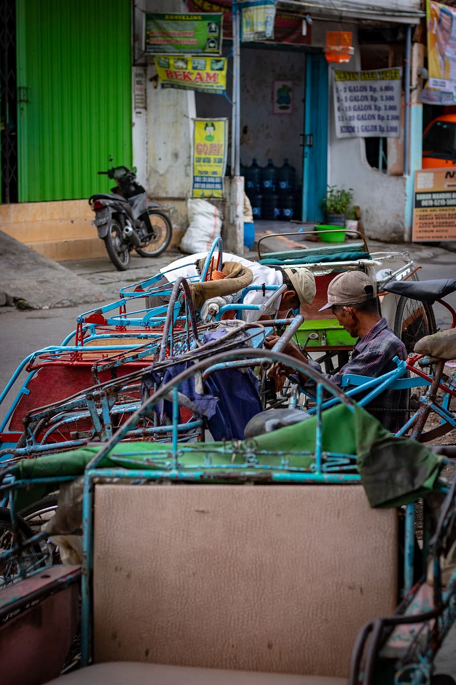 man sitting on pedal trike near buildings, street photography