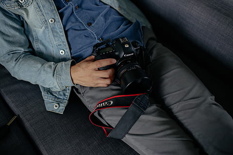 man holding camera lying on bed, electronics, human, person, cushion HD wallpaper