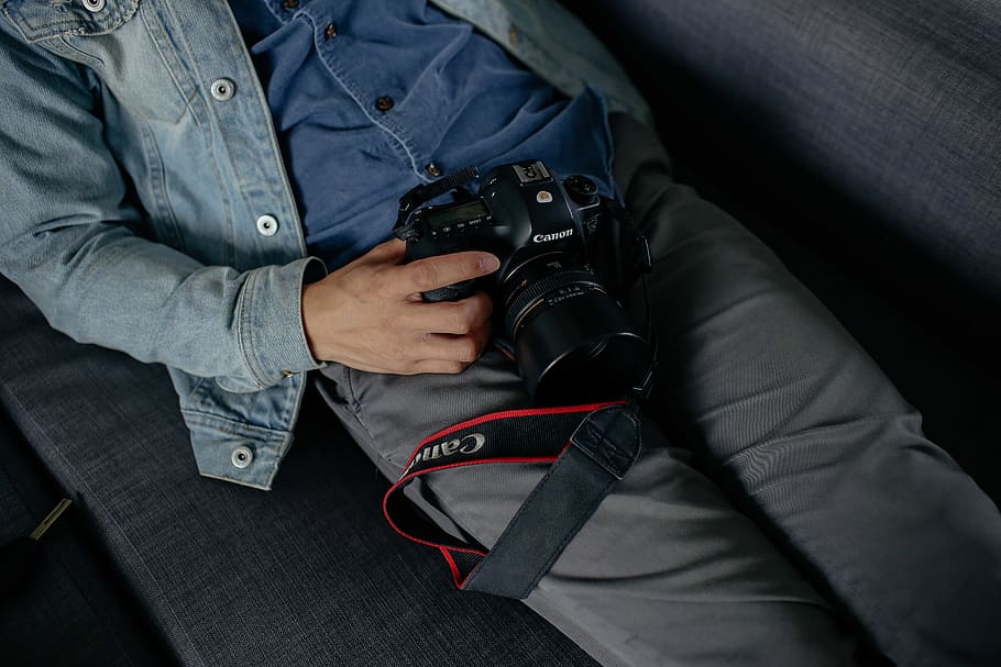 man holding camera lying on bed, electronics, human, person, cushion HD wallpaper