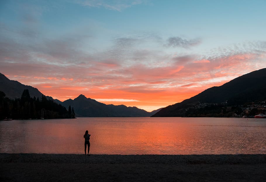 Silhouette Photo of Person Standing Near Body of Water, background HD wallpaper