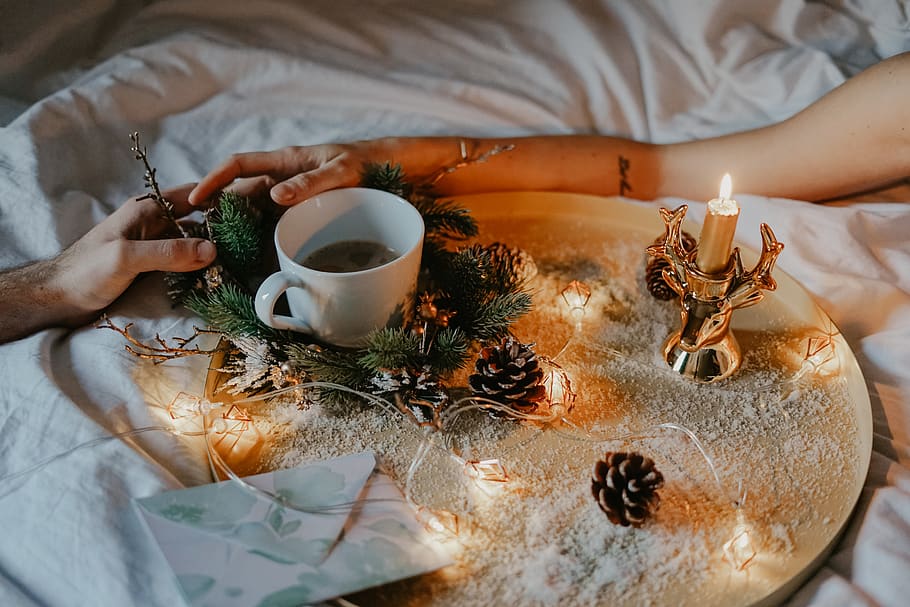 white ceramic cup on table beside pine cones, human hand, one person HD wallpaper