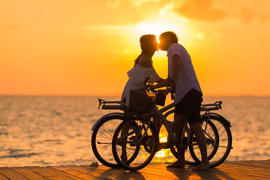 Photography of Man Wearing White T-shirt Kissing a Woman While Holding Bicycle on River Dock during Sunset, HD wallpaper