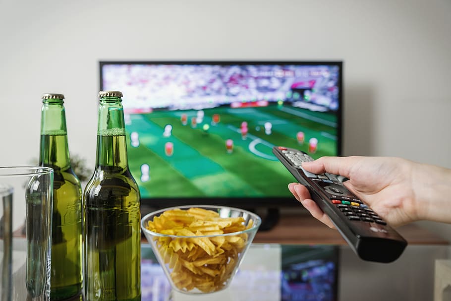 Watching football match on tv with remote controller., food and drink