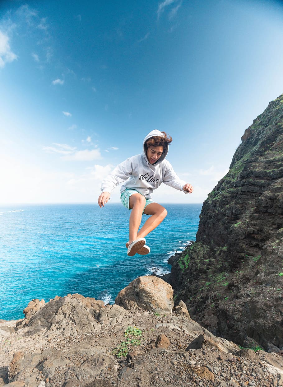 Man Wearing Gray Hoodie Jumping at Rock, cliff coast, cliffside, HD wallpaper