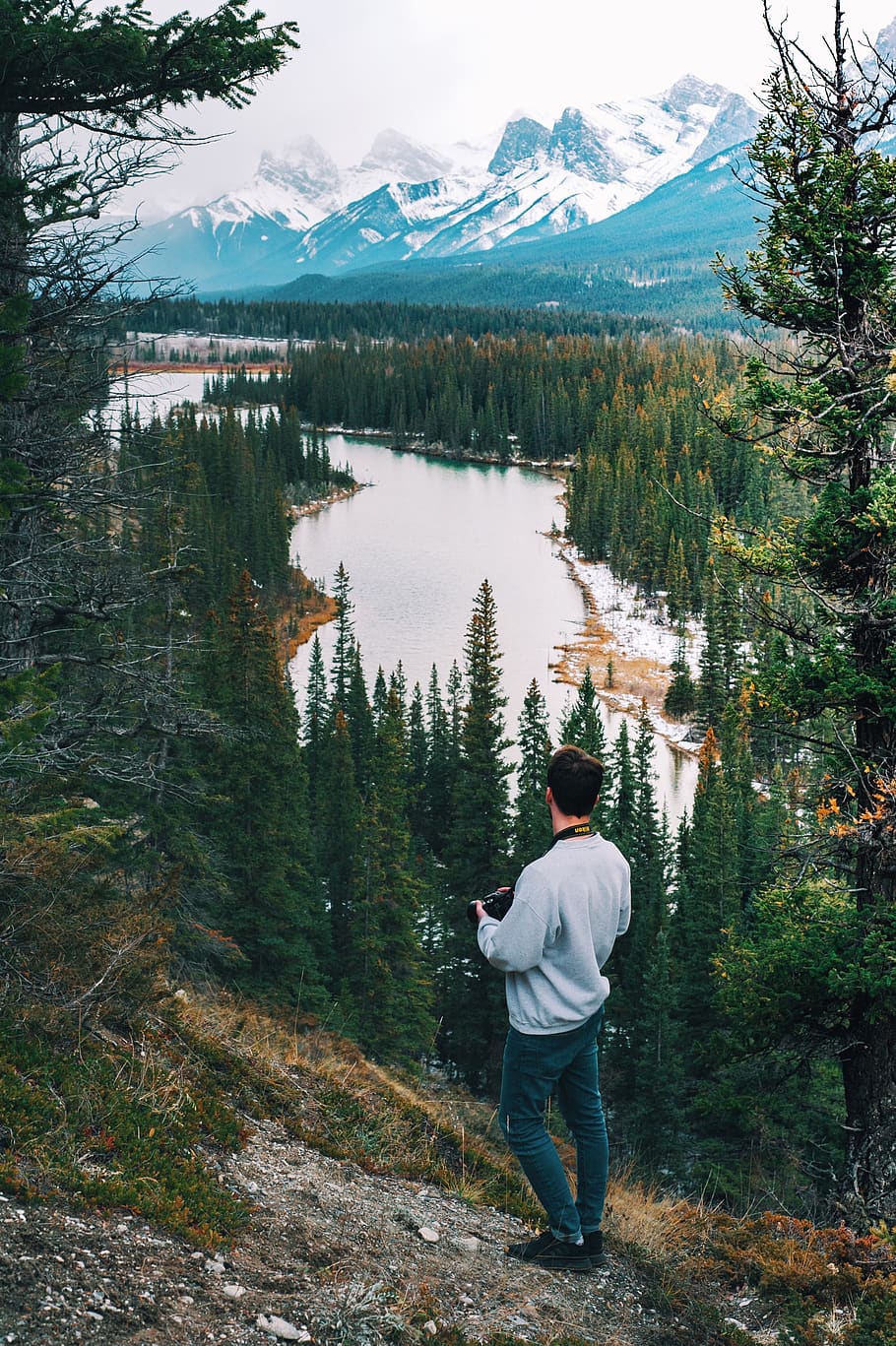 man wearing sweater standing on cliff watching river, person, HD wallpaper