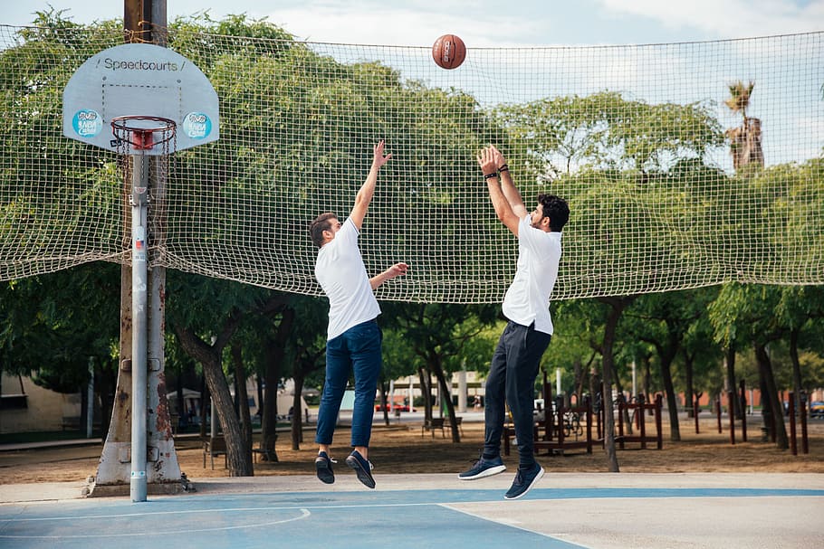Two young men playing basketball in the day time, 20-25 year old