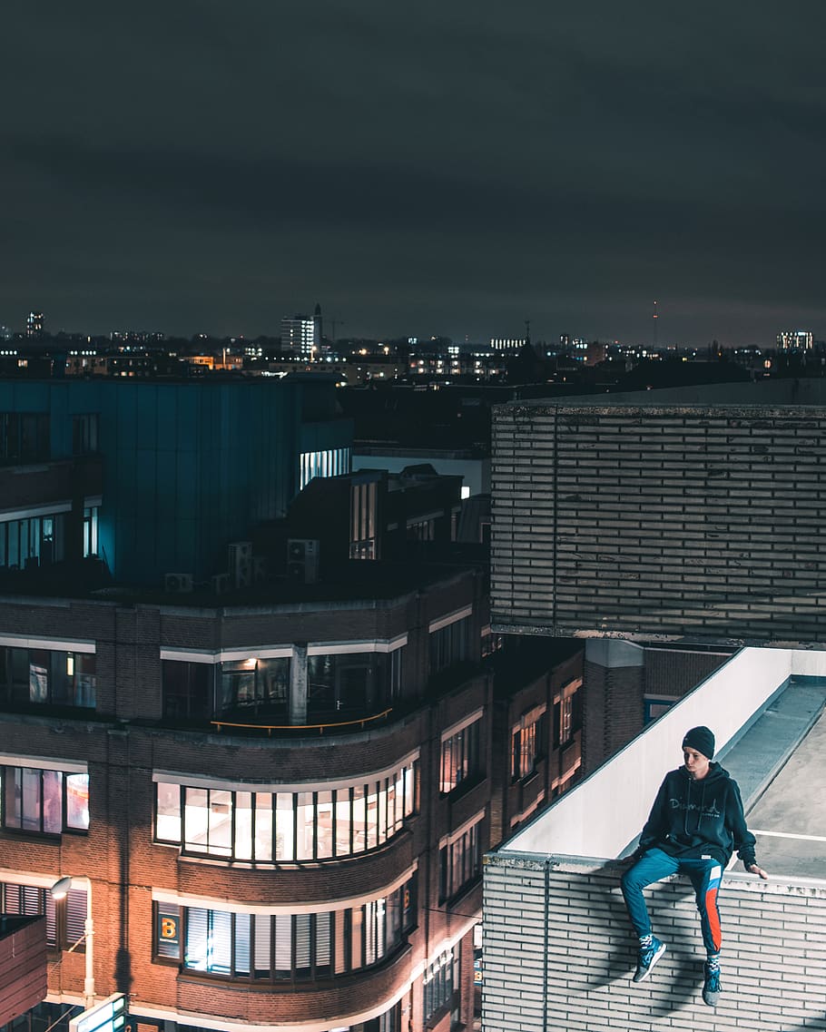 Man Wearing Black Jacket Sitting On Building Rooftop At Nighttime HD wallpaper