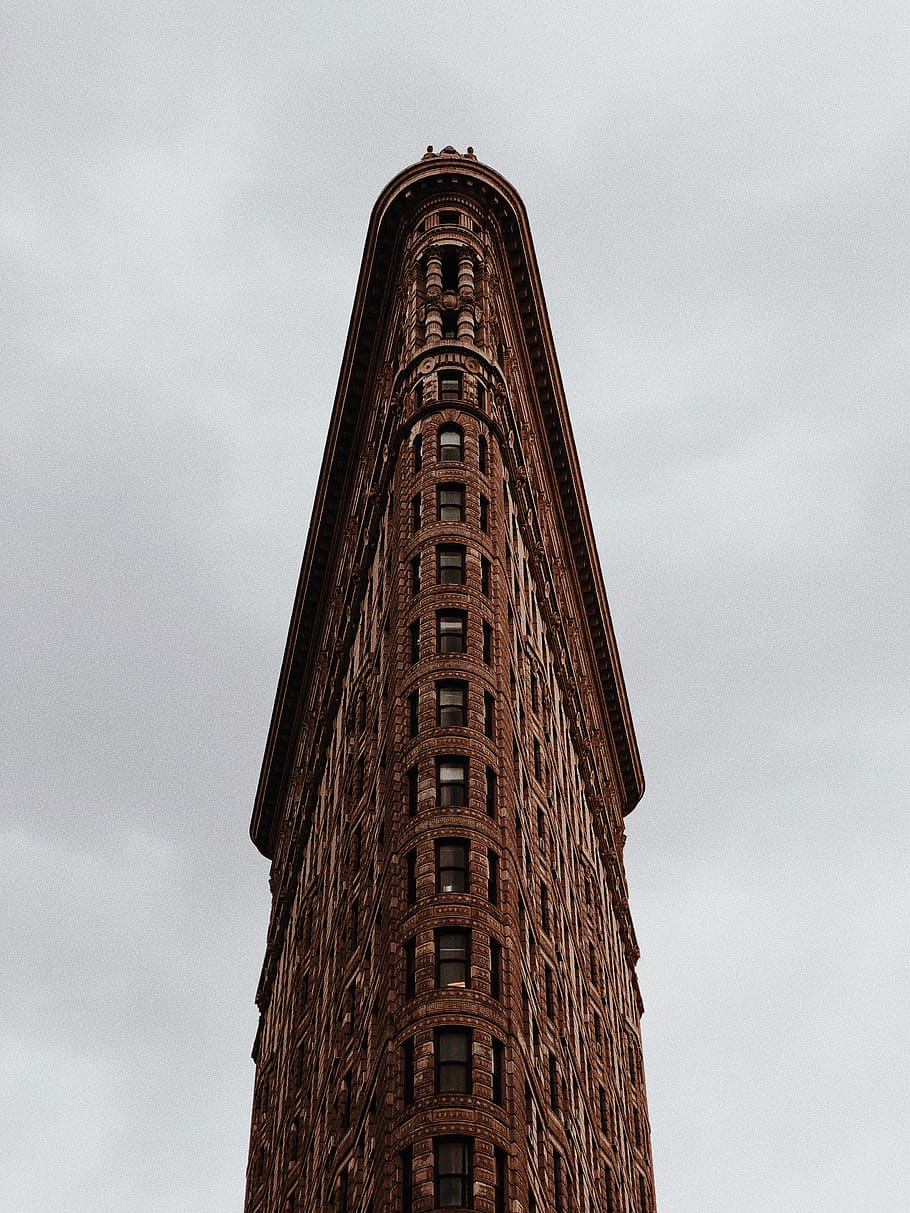 tall triangular shaped brown brick building under grey sky, low angle view HD wallpaper