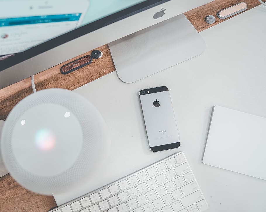 space gray iPhone 5s beside silver iMac, keyboard, desk, light