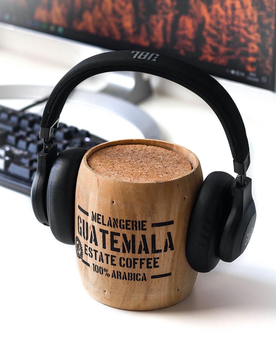 brown Guatemala wooden mug and black JBL headphones on it, text