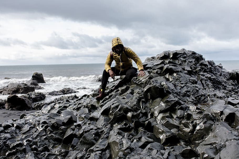 Selective Color Photography of Man Wearing Hoodie on Stone Behind Body of Water HD wallpaper