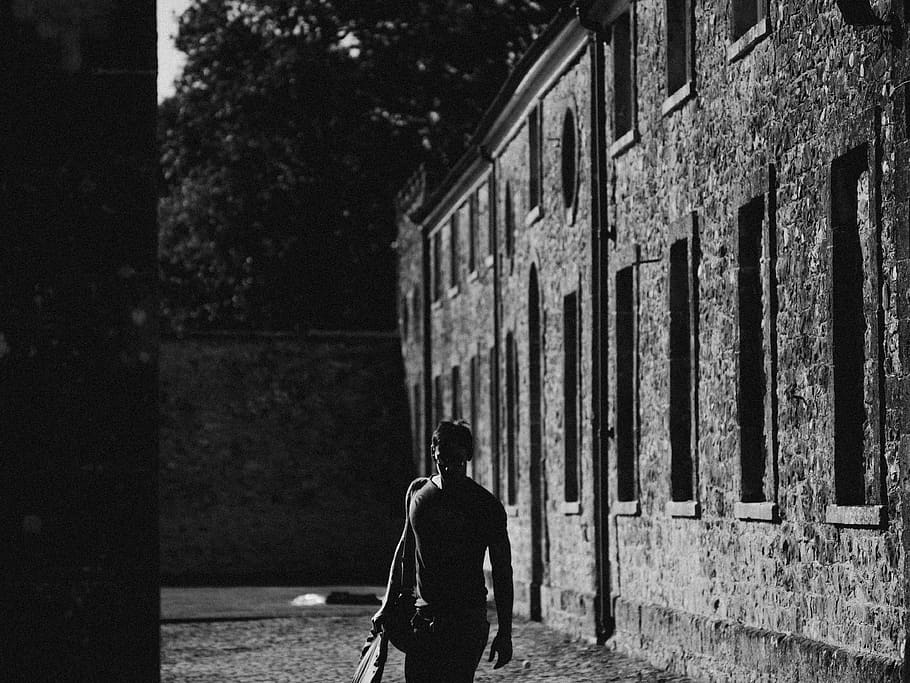 Man Walking Beside Concrete Wall, architecture, black and white HD wallpaper