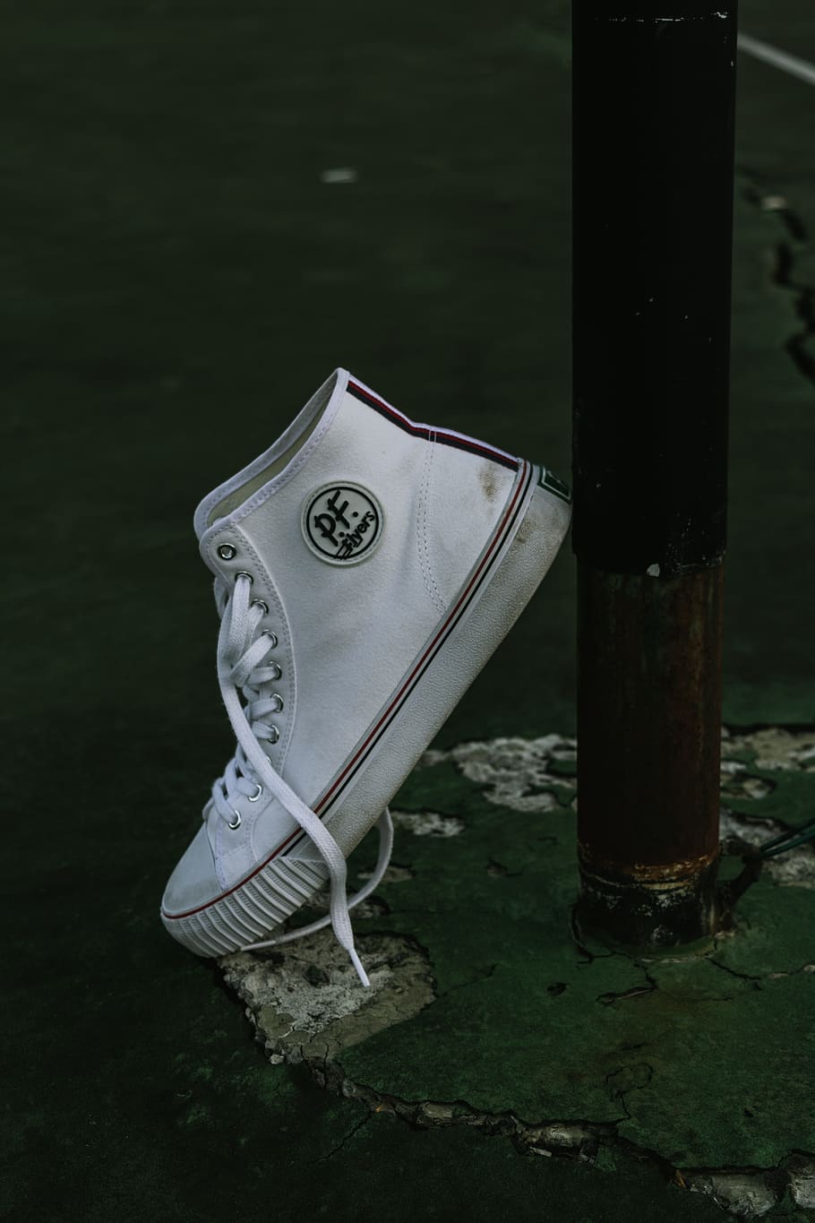 unpaired white PF high-top sneaker leaning on black post, apparel