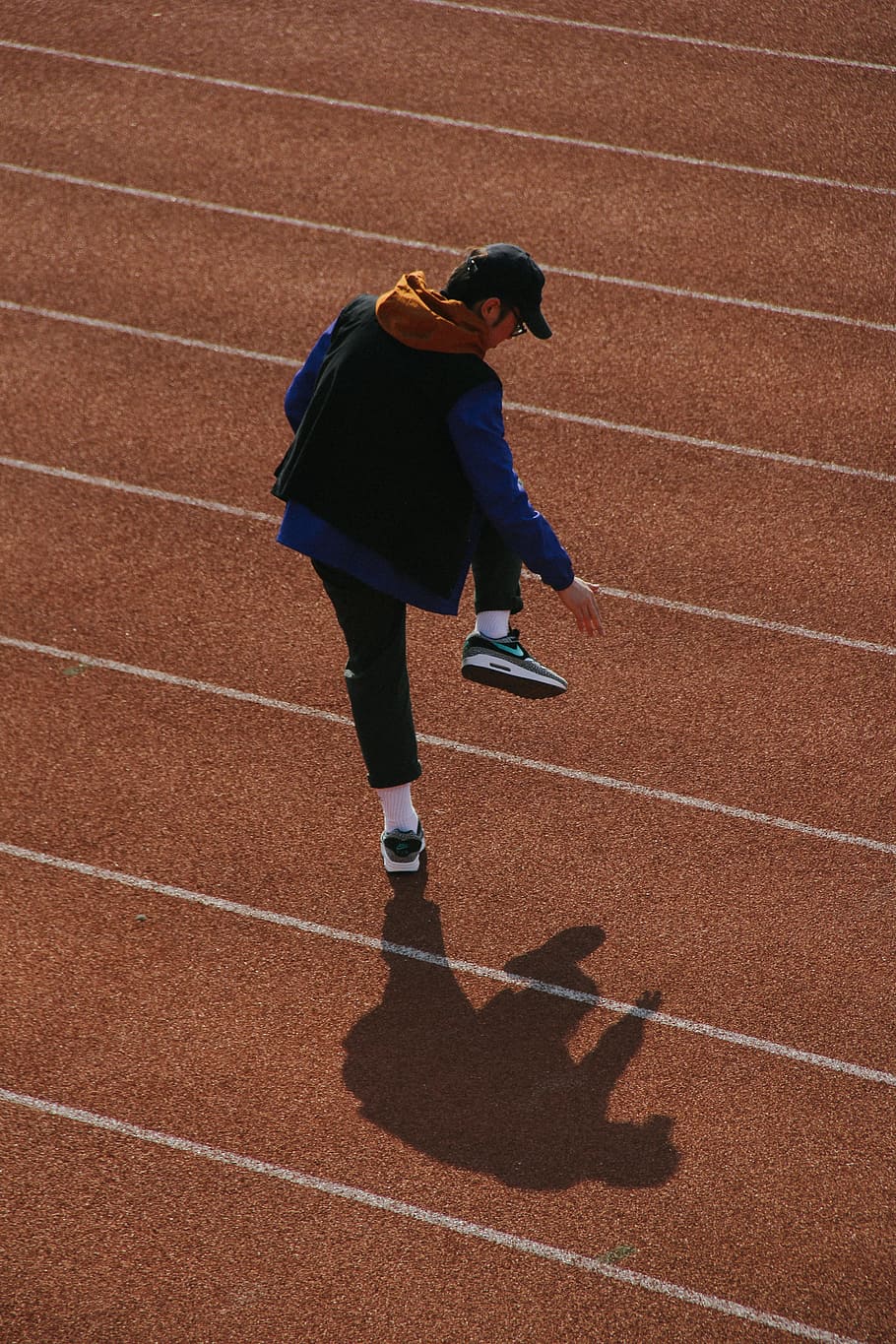 man walking on track field, person, shadow, play, fun, line, sport HD wallpaper