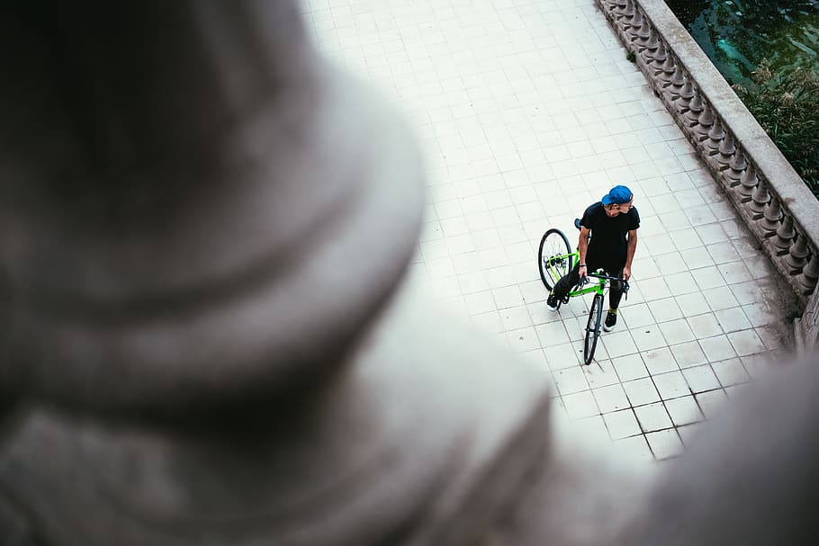 A young Caucasian male cyclist wearing blue cap halts on the street, HD wallpaper