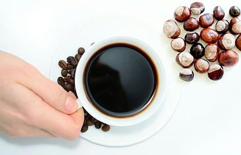 Overhead view of cup of coffee and nuts, with hand holding mug. HD wallpaper