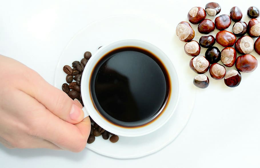 Overhead view of cup of coffee and nuts, with hand holding mug. HD wallpaper
