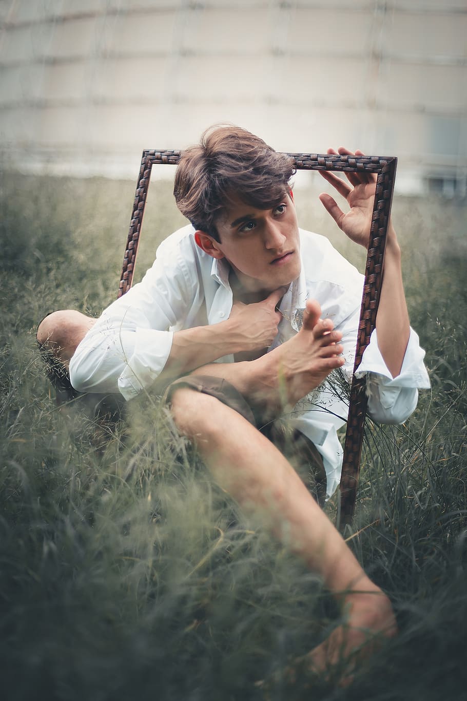 Man in White Dress Shirt Holding Frame Sitting on Green Grass Covered Ground HD wallpaper