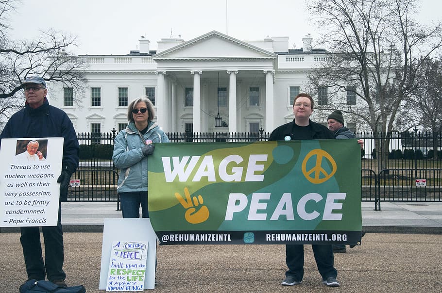 people holding Wage Peace signage in front of white concrete building during daytime, HD wallpaper