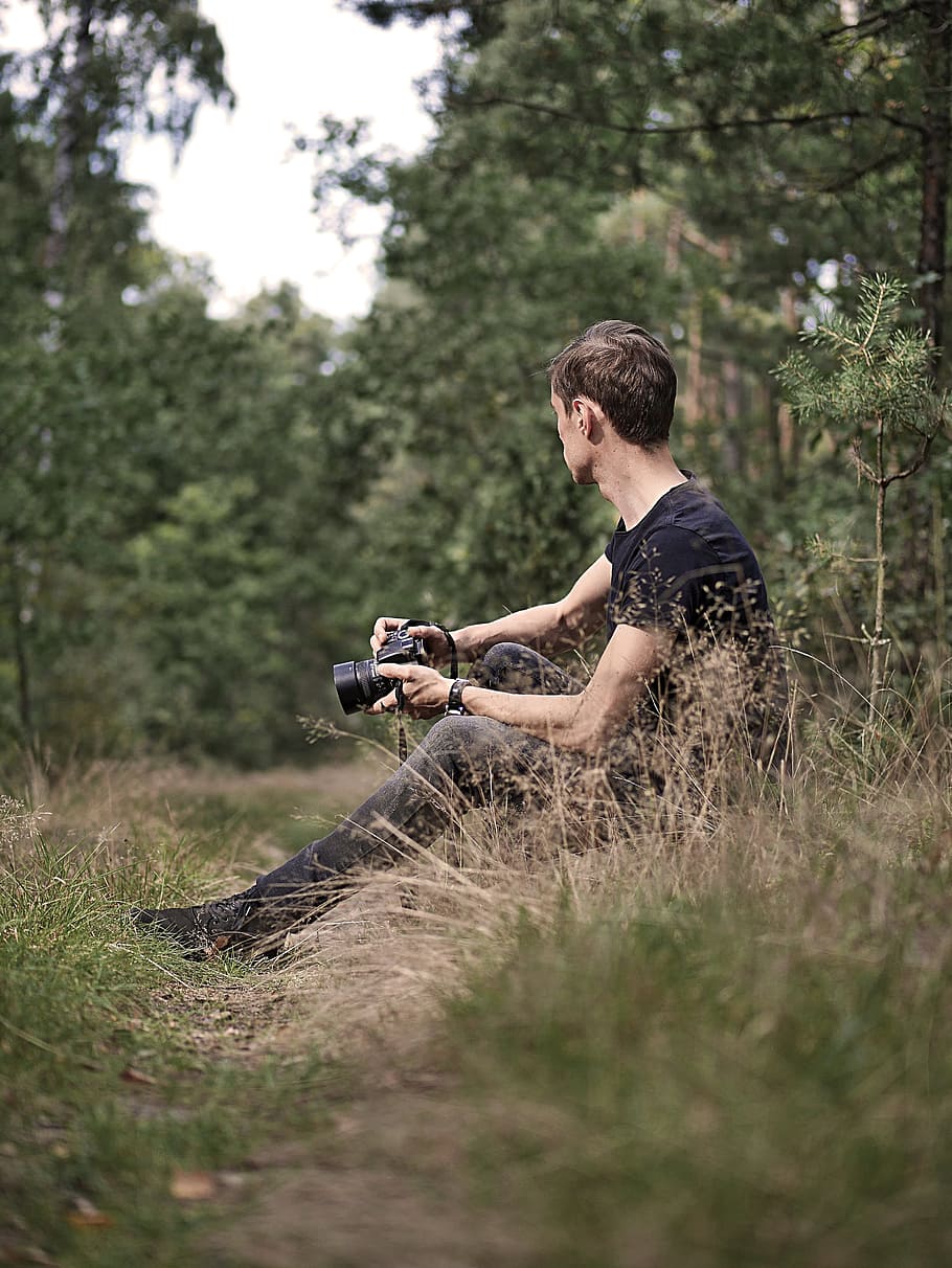 Man Holding Camera Sitting on Green Grass, daylight, outdoors HD wallpaper