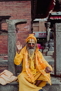 man wearing yellow long-sleeved coat sitting near pillar, old HD wallpaper
