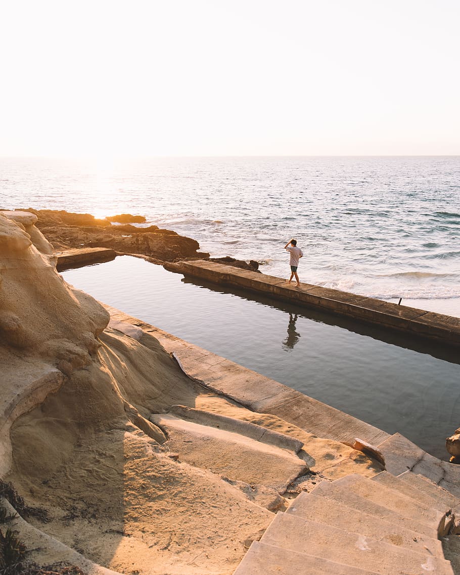 man walks on side of infinity pool in beach, photography, sunset HD wallpaper