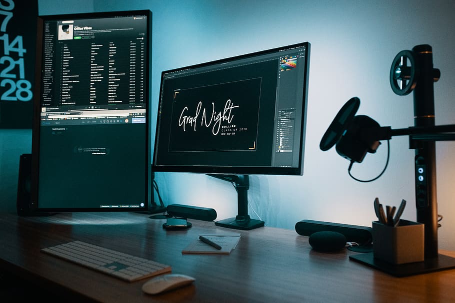 two flat screen computer monitors on table, indoors, no people