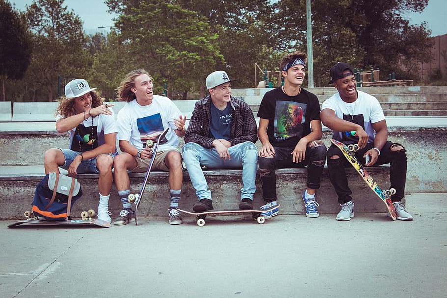 five group of men sitting together with their skateboards, kids