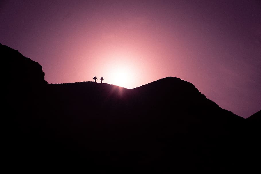 Silhouette Photo of Two Persons Standing on Black Mountain Peak HD wallpaper