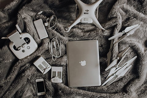 Drone, laptop and accessories lie on the bed ready for travel HD wallpaper