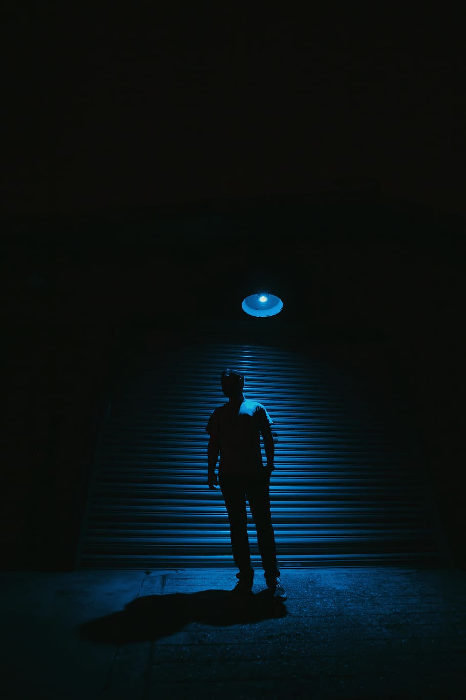 person standing near roll-up door with light turned-on, human