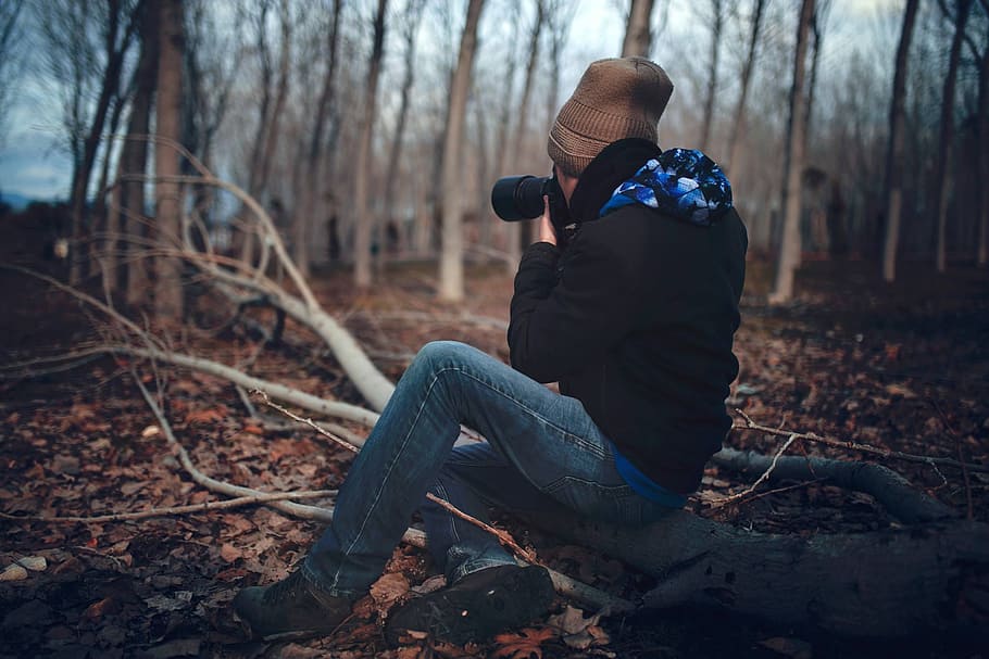 Man Wearing Black Jacket and Blue Jeans Sitting on Tree Branch HD wallpaper