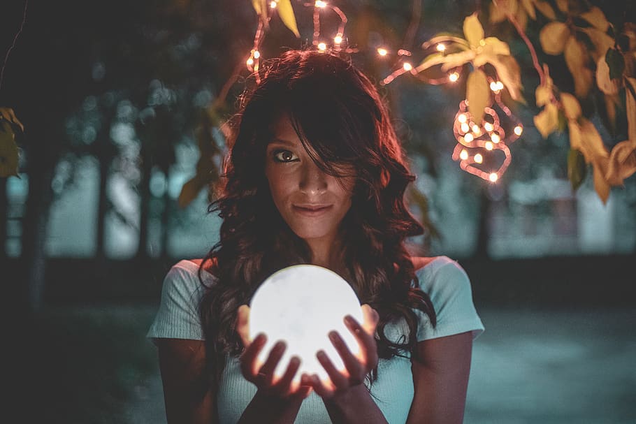 Woman Holding Lighted Glass Ball Under String Lights, beautiful