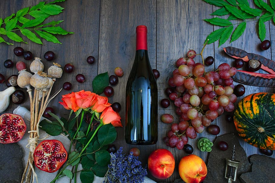 Wine Bottle Beside Grapes, Roses and Several Fruits on Brown Wooden Surface HD wallpaper