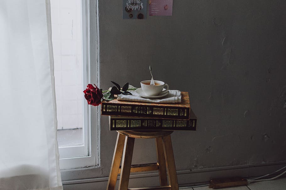 white ceramic teacup on saucer plate on books on stool near window at room HD wallpaper