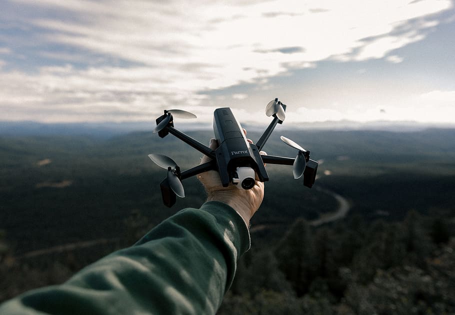 person holding black and gray drone, hand, sweater, mountain HD wallpaper