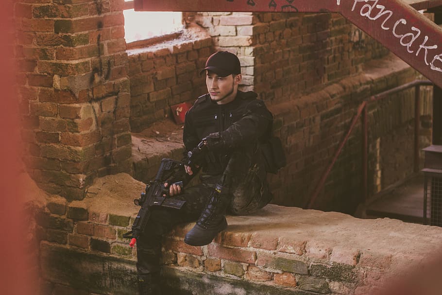 Man Holding Toy Gun, bricks, person, uniform, weapon, wear, real people HD wallpaper