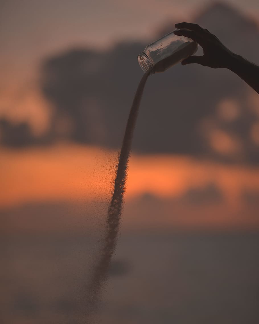 person holding clear glass jar, sand, hand, pour, sunset, falling HD wallpaper