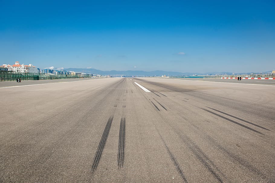 wheel marks on gray concrete pavement during daytime, runway