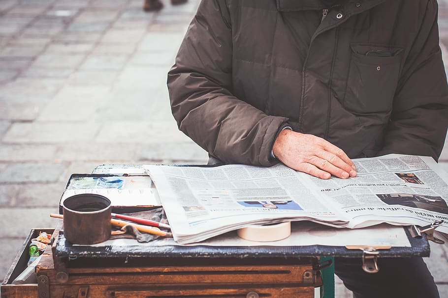 Reading a newspaper article. Человек носит бумаги.