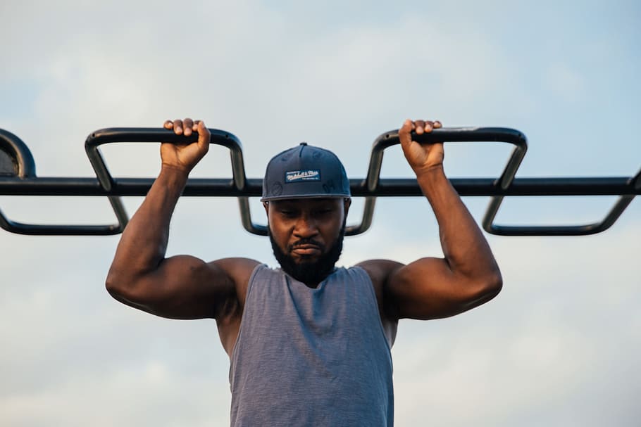 A young african man doing chin-up exercise outdoors, 25-30 year old