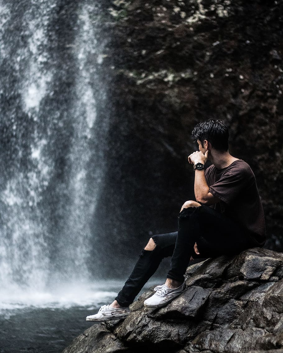 man sitting near waterfalls, person, outdoor, rock, sneaker, shoe, HD wallpaper