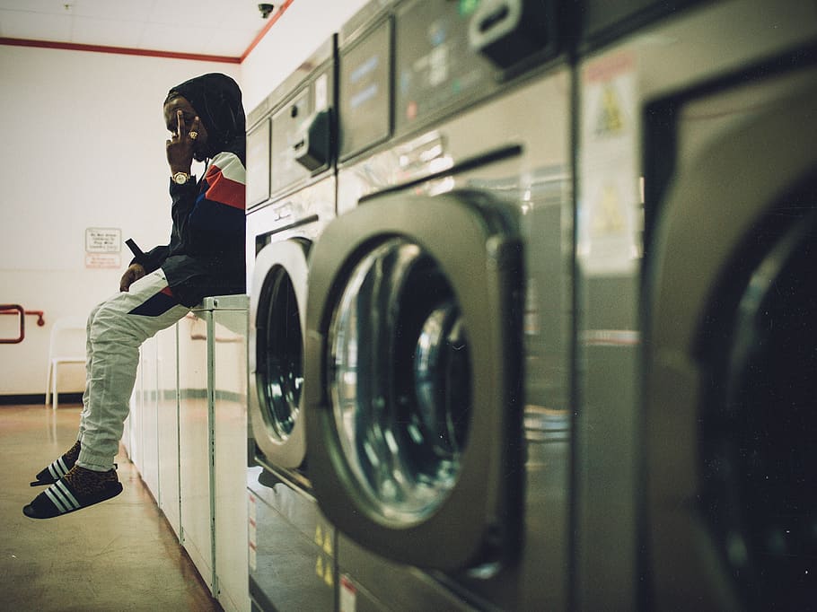man sitting on laundry appliances, washing machine, household equipment