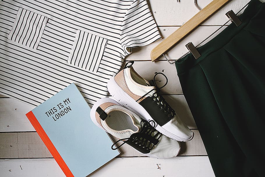 pair of white-and-black low-top sneakers near black skirt on brown clothes hanger top view photography