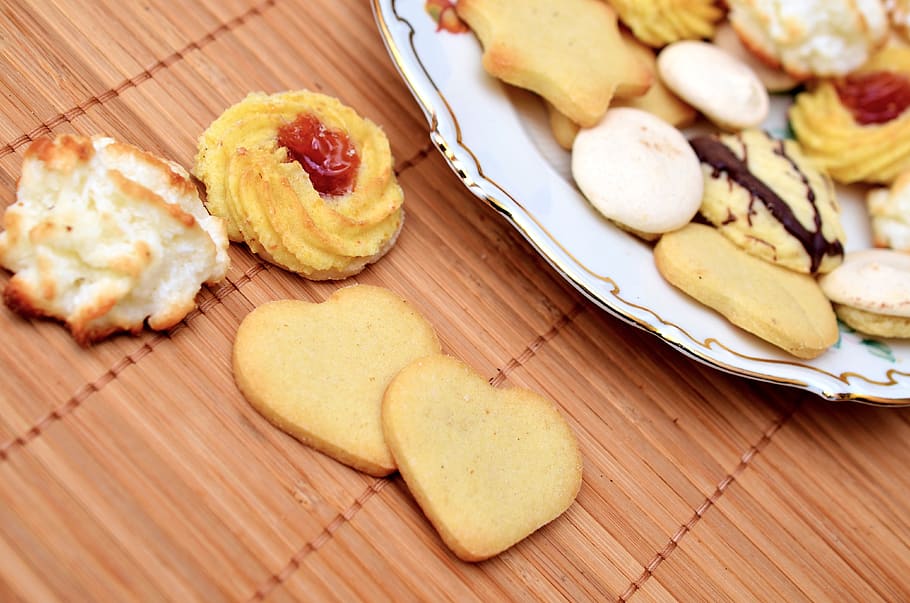 Assorted Baked Cookies on White Ceramic Plate on Top of Brown Bamboo Mat HD wallpaper