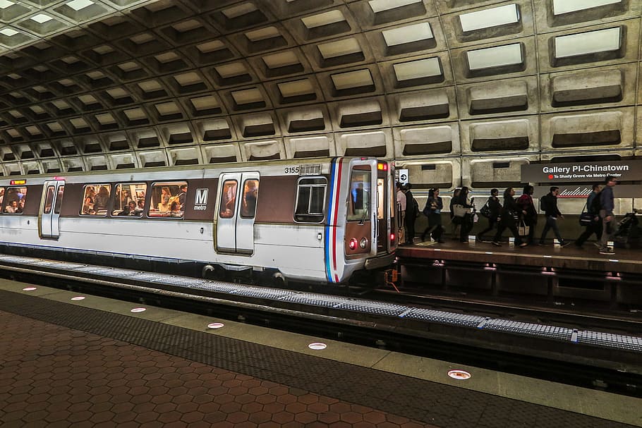 Trains arriving and leaving in DC metro station with riders on platform.