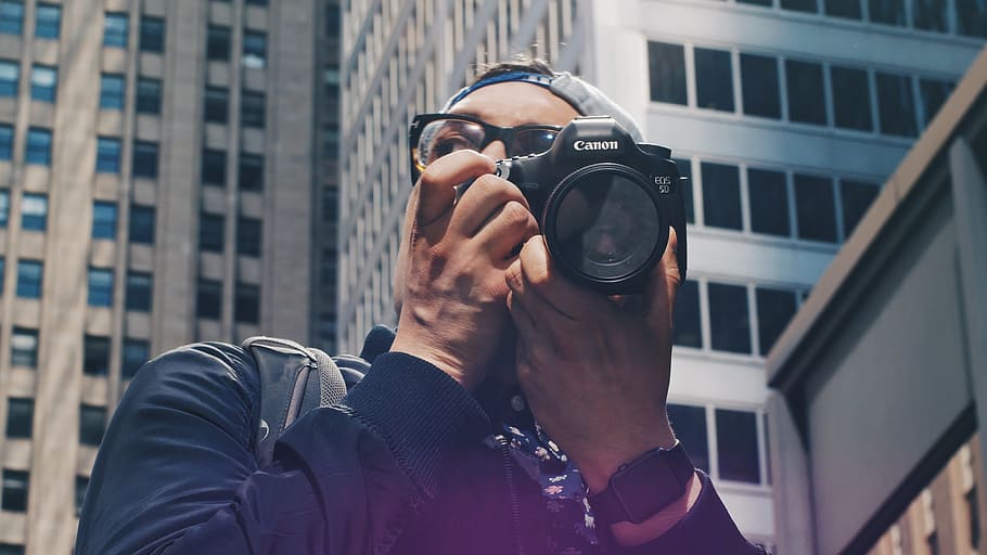 man holding Canon DSLR camera, photographer, city, building, portrait