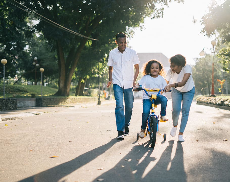 Man Standing Beside His Wife Teaching Their Child How to Ride Bicycle HD wallpaper