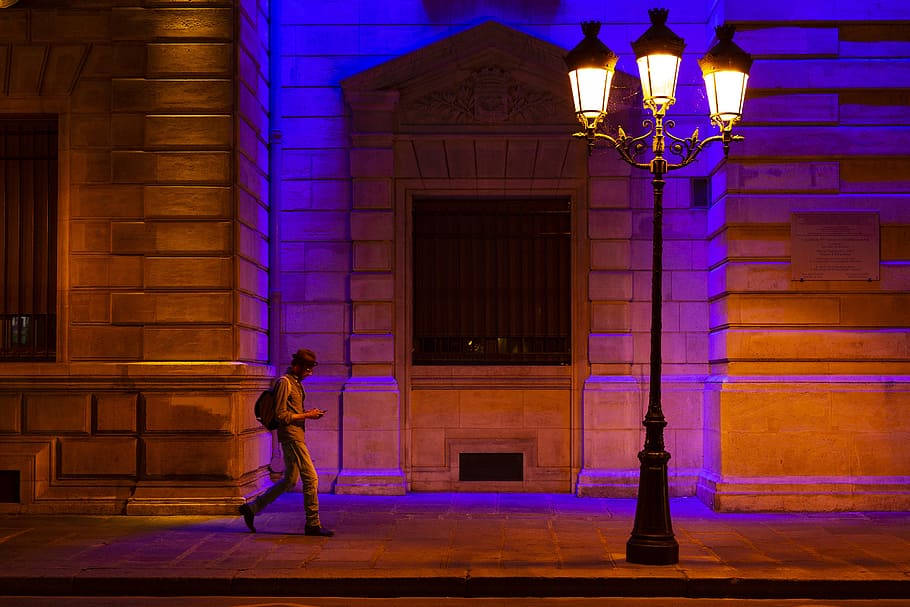 man walking at sidewalk with turned on streetlight, night, building