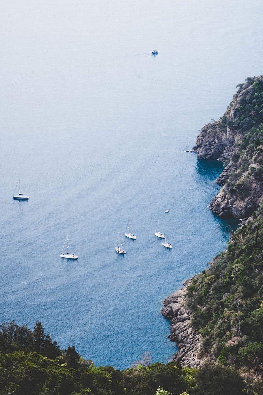 six white boats sailing beside an island, cliff, blue, sea, water
